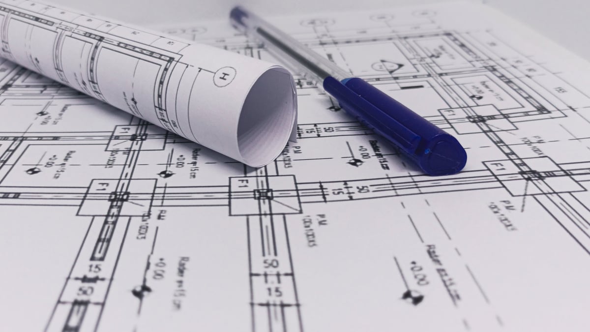 Rolled blueprint and pen on construction plans, representing architecture, engineering, design, and building projects