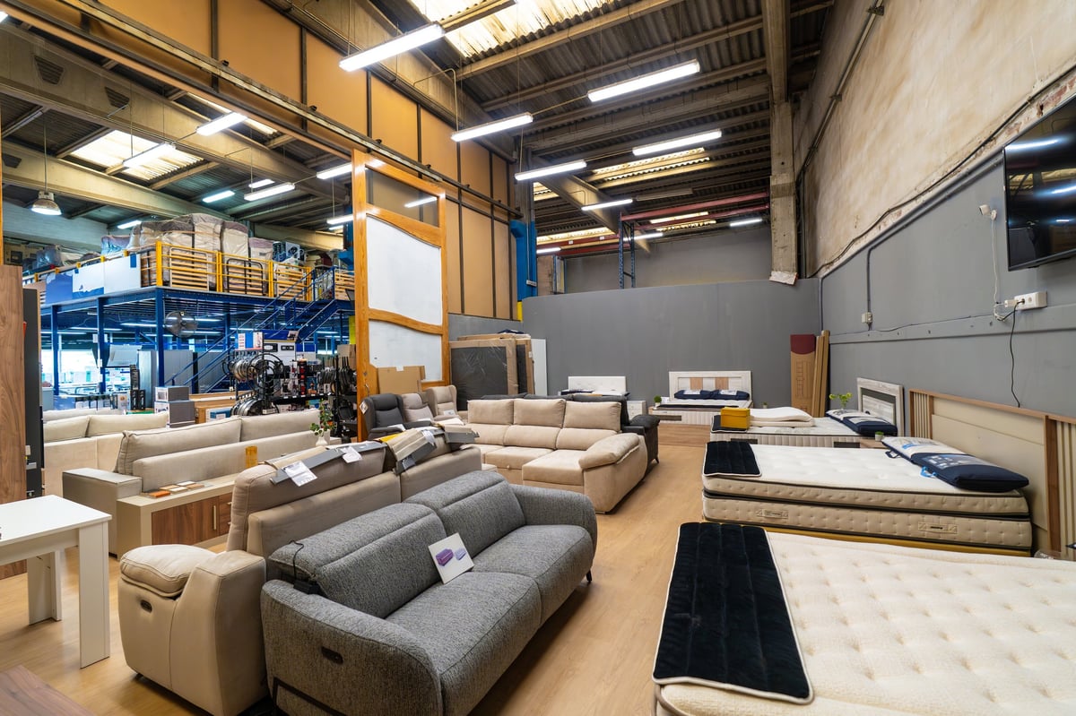 Large retail furniture store showroom displaying a wide selection of modern sofas, beds, and mattresses