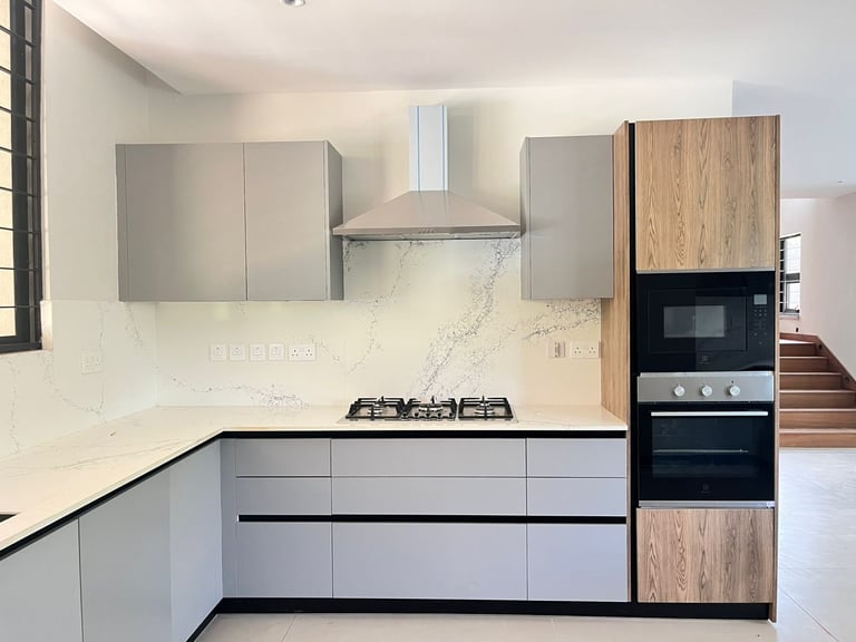 Modern kitchen with white and wood cabinetry, marble backsplash, gas cooktop, and stainless steel range hood