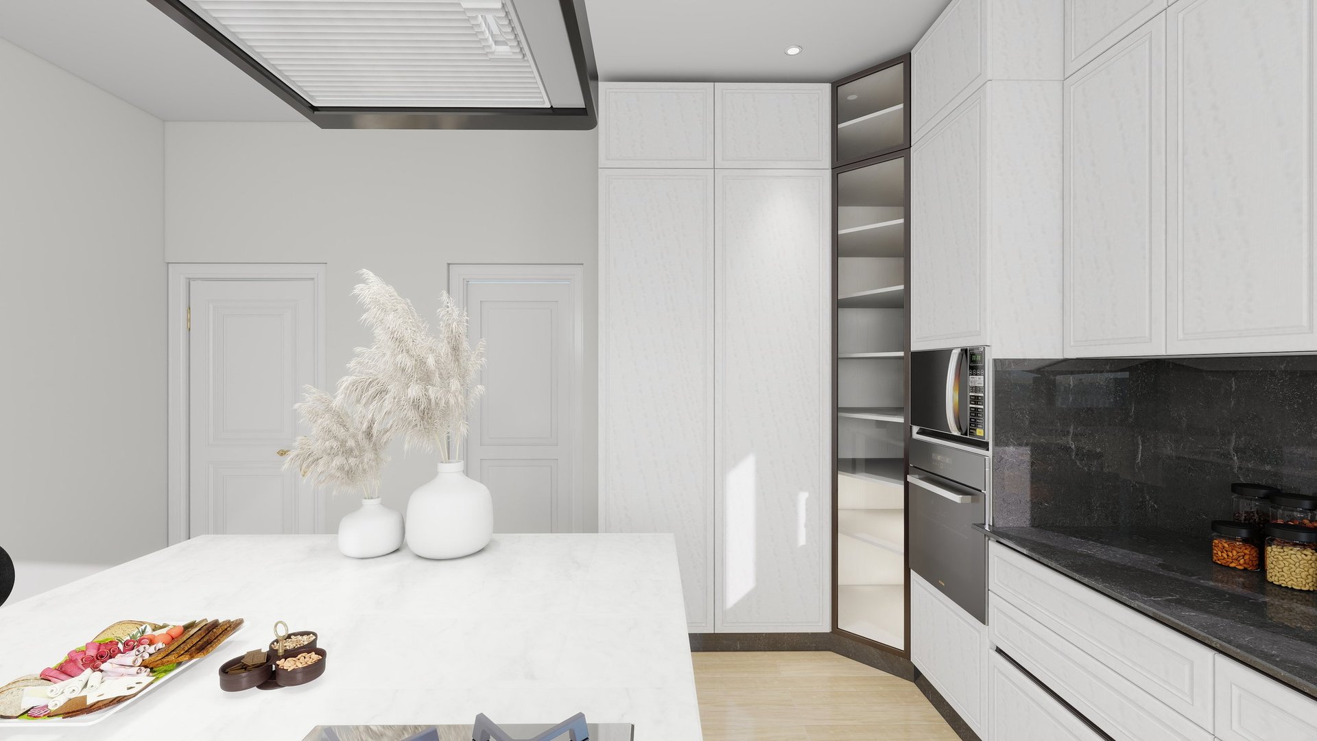 Modern white kitchen with black accents, white island counter, built-in appliances, decorative pampas grass, and food items on counter