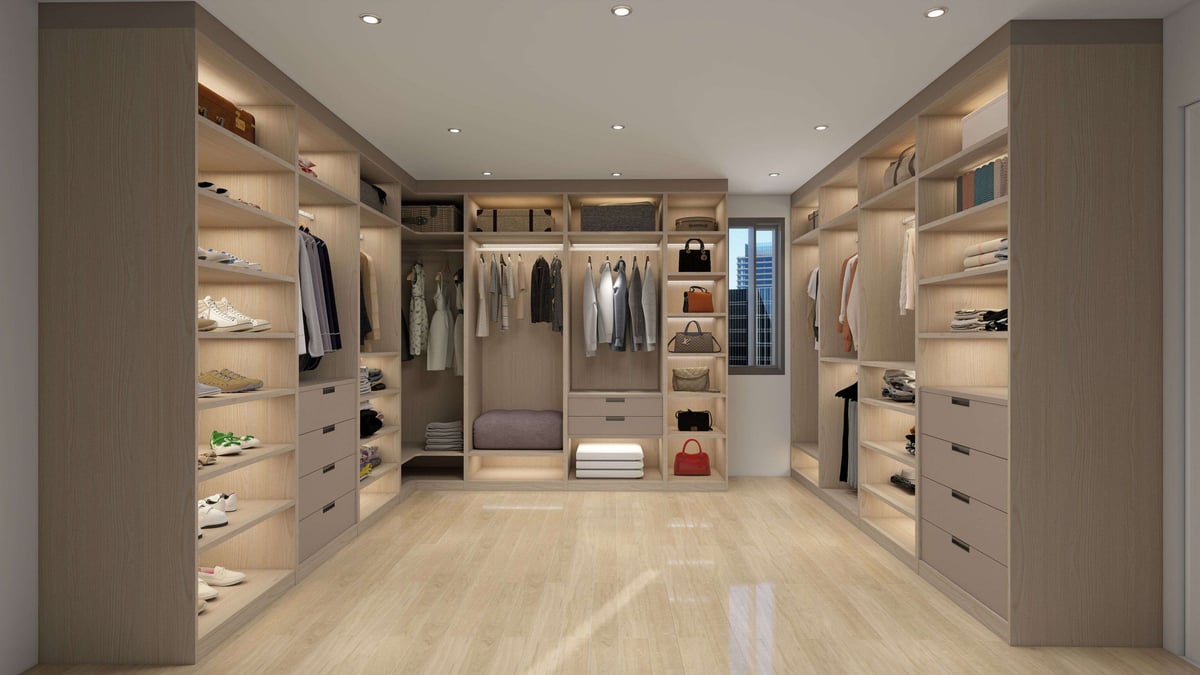 Modern luxury walk-in closet with beige cabinetry, clothing racks, shelving, and light wood flooring throughout