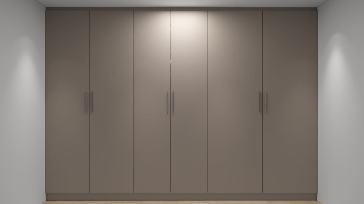 Modern built-in wardrobe with five taupe-colored doors and minimalist handles against white walls with accent lighting