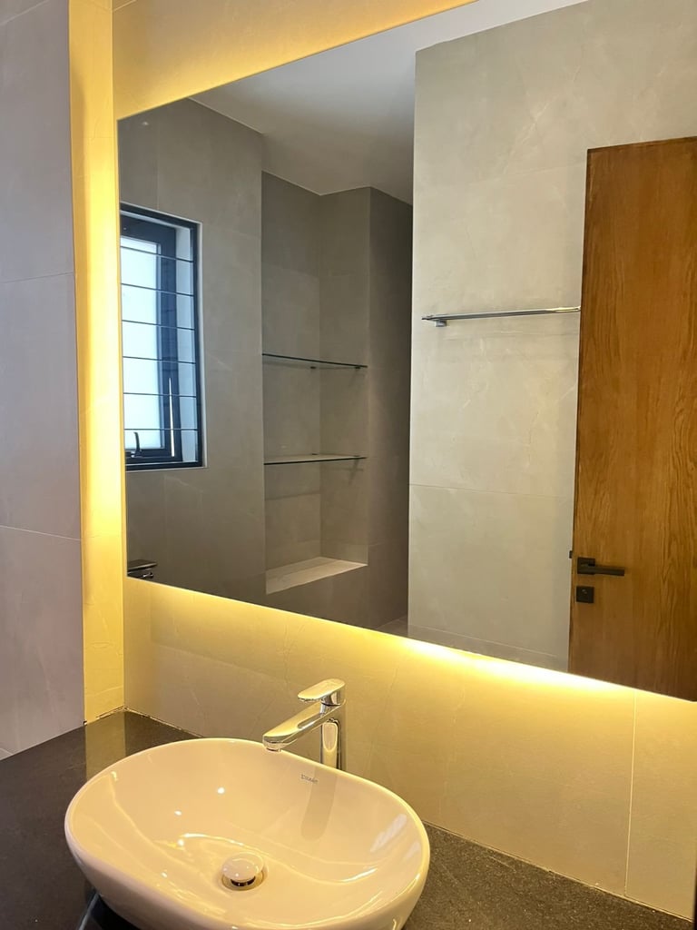 Modern bathroom with illuminated mirror, white round sink, metal faucet, and wooden door visible on the right