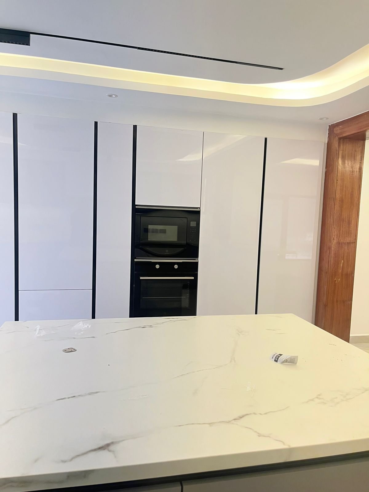 Modern kitchen with white marble countertop, built-in black ovens, and integrated cabinetry with black trim accents
