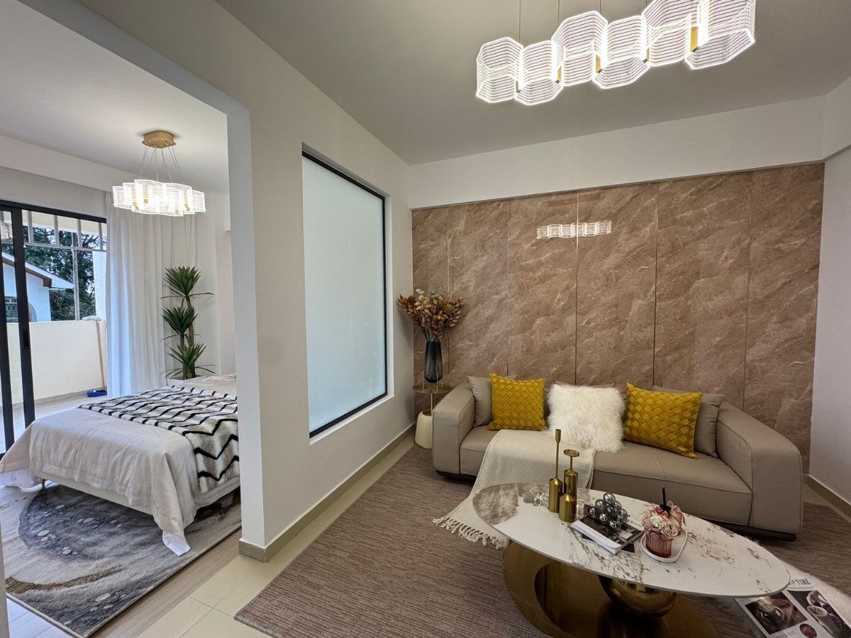 Modern bedroom and living room suite with beige sofa, yellow accent pillows, wall-mounted mirror, and contemporary lighting fixtures