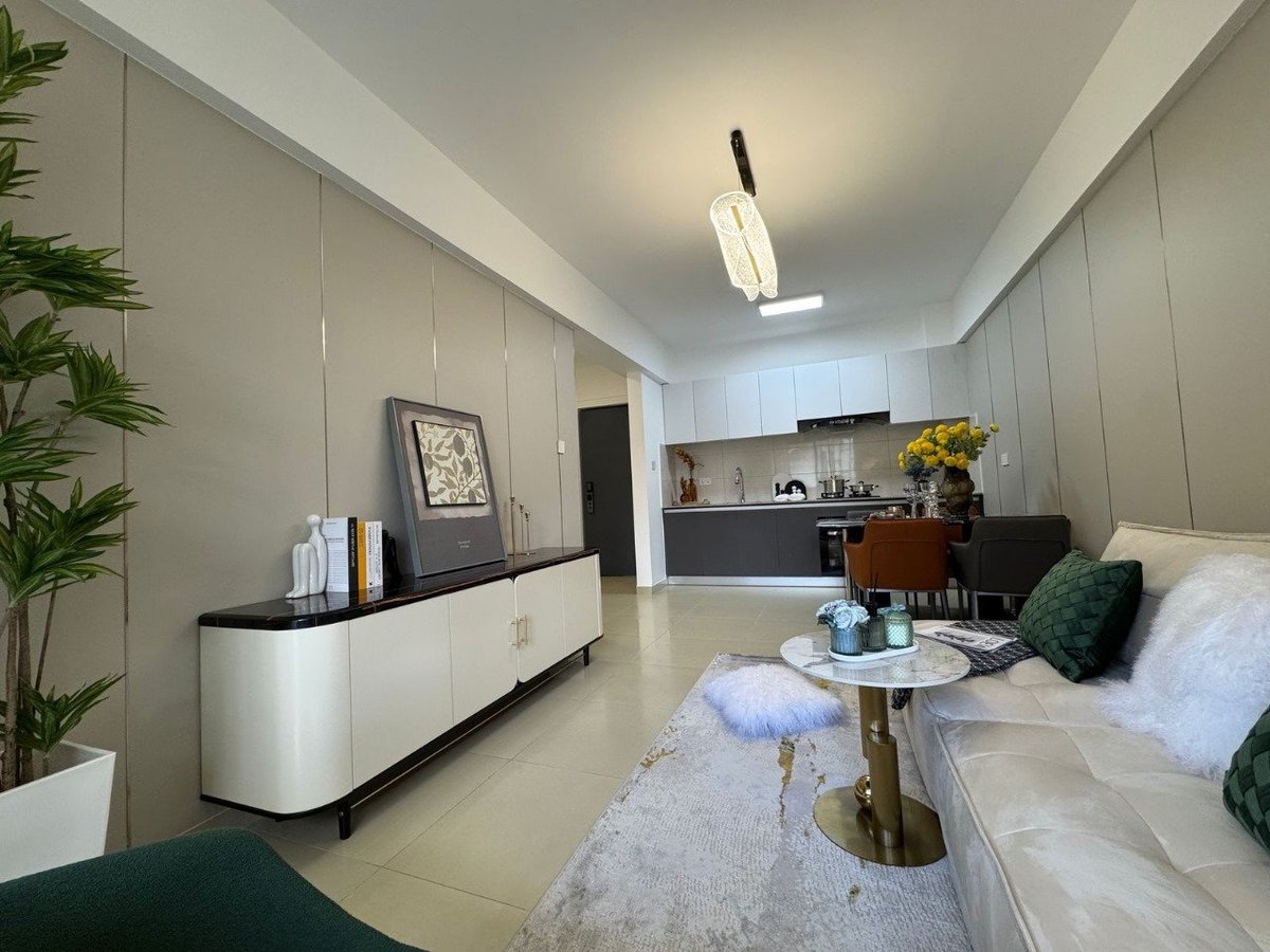 Modern minimalist studio apartment with beige walls, white bed, kitchen area, decorative plants, and contemporary furnishings
