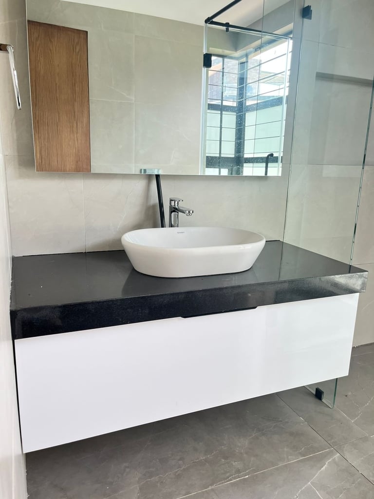 Modern bathroom vanity with white bowl sink on black countertop, mirrored medicine cabinet, and glass shower enclosure