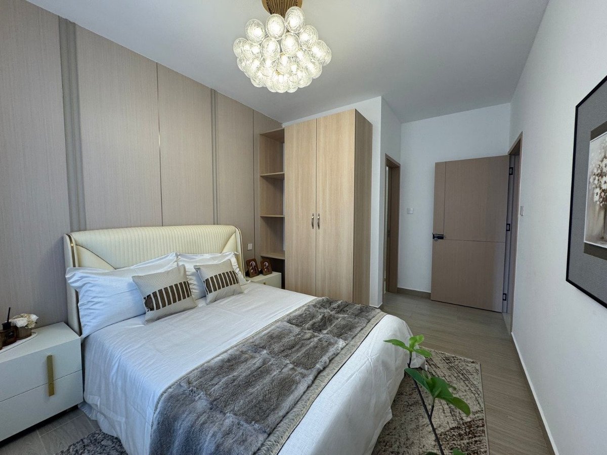 Modern bedroom with white bed, wooden wardrobe, pendant chandelier, and minimalist decor
