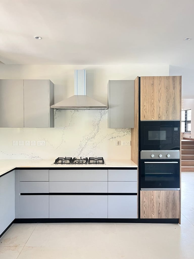 Modern kitchen with light gray cabinetry, wood-toned upper cabinets, marble backsplash, built-in black microwave and oven, gas cooktop, and stainless steel range hood