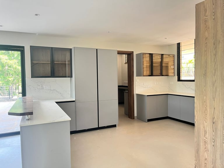 Modern kitchen showroom display with white cabinetry, gray countertops, and wood-grain accent wall