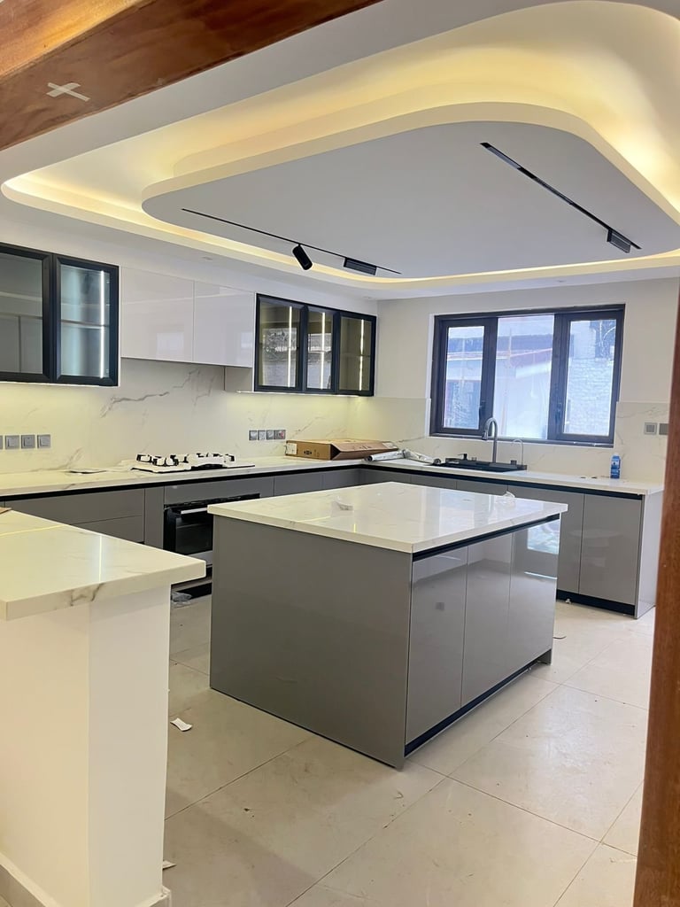 Modern kitchen with white and gray cabinetry, central island, stainless steel appliances, and curved ceiling with ambient lighting