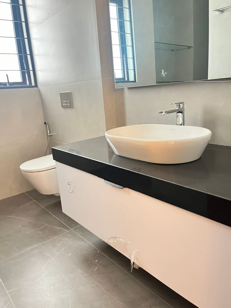 Modern bathroom with round white vessel sink on black vanity, white toilet, large mirror, and tile flooring